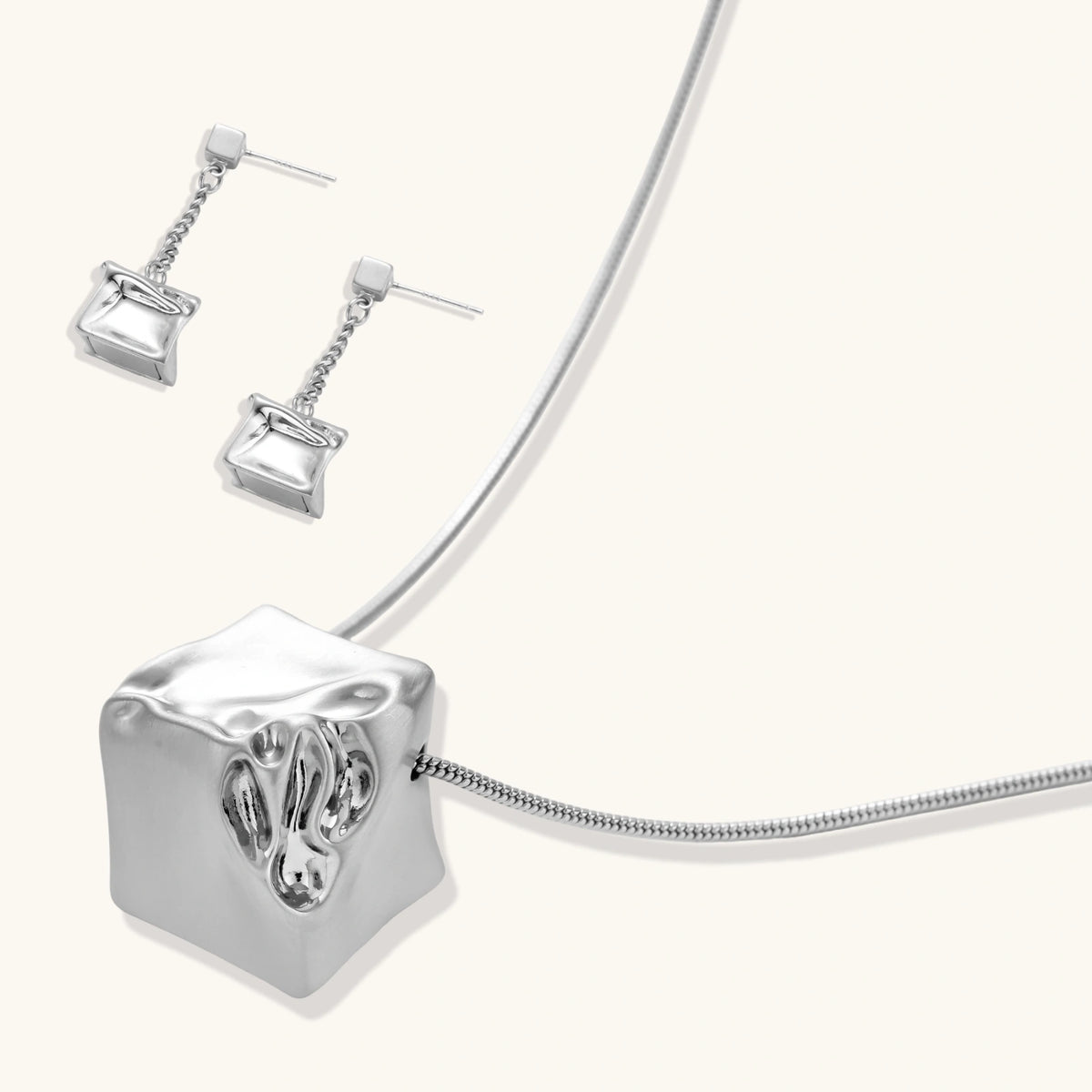 Geometric jewelry set with textured cube pendants on chains, featuring eco-zinc alloy in silver and gold finishes.