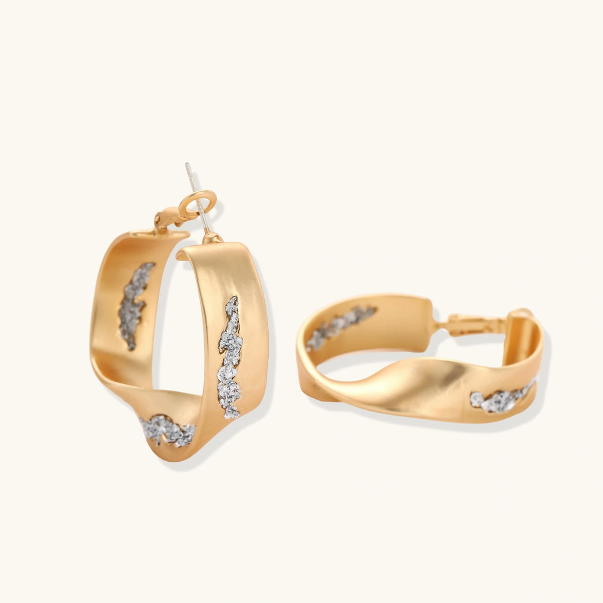Sculptural wavy hoop earrings with crystal details and organic curved silhouette in gold and silver variants