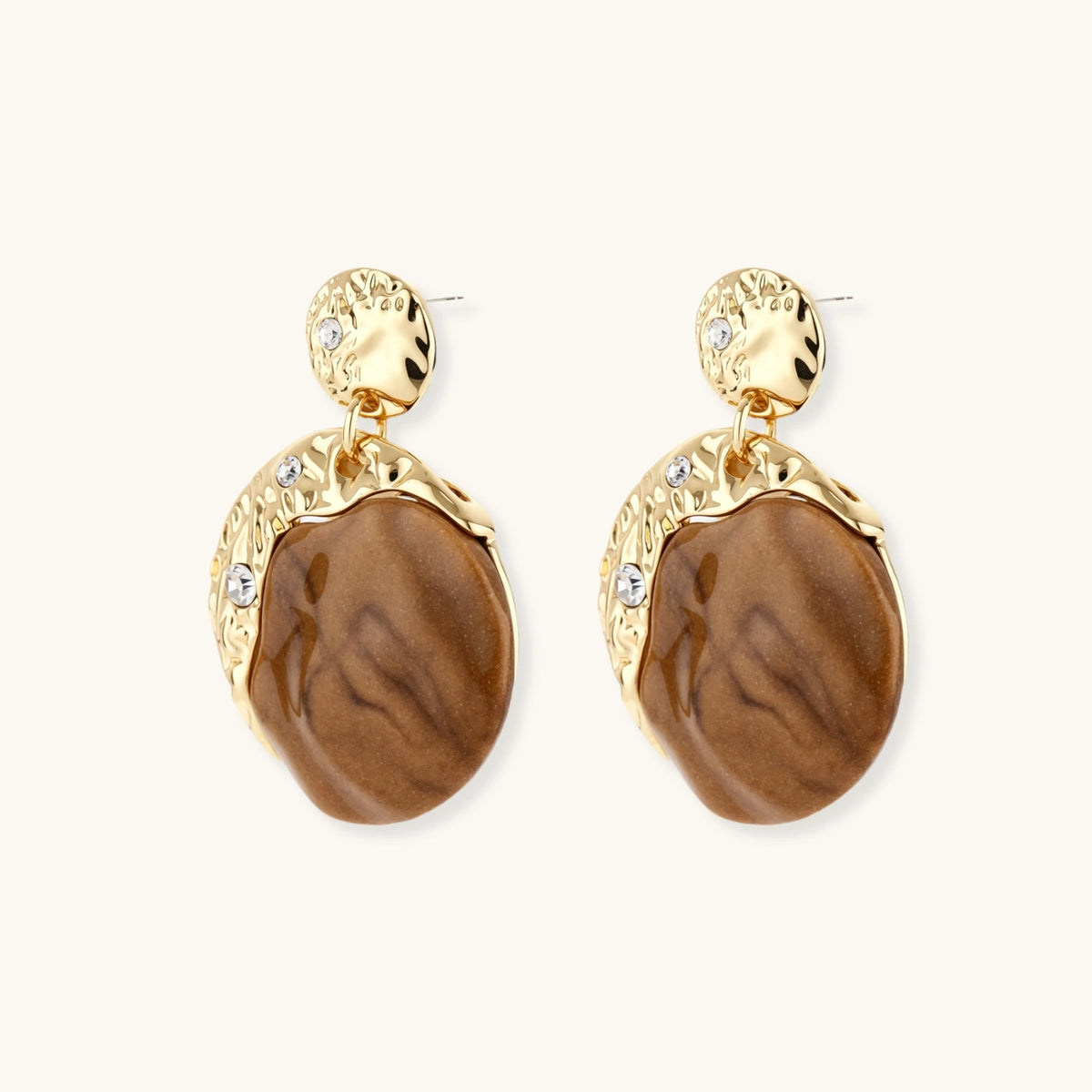 Gold-toned dangle earrings with organic brown resin stones and crystal accents on white background