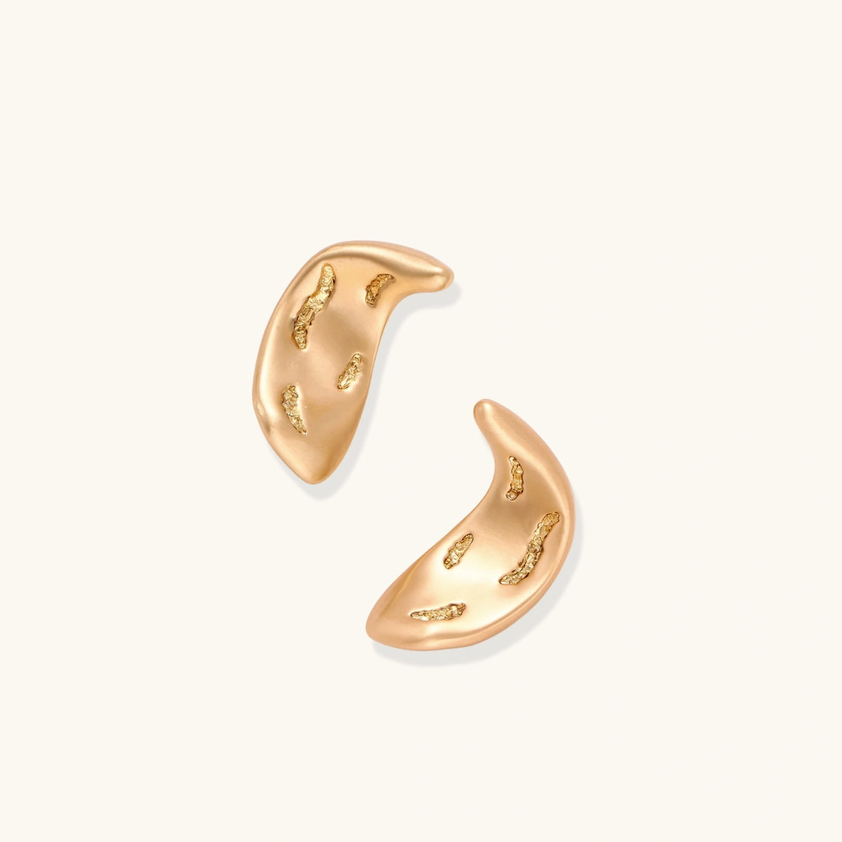 Pair of gold crescent moon-shaped stud earrings with textured surface details on cream background.
